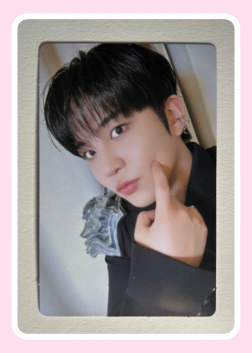 Jongho Ateez with a stylish haircut and earring, posing with a finger on his cheek.