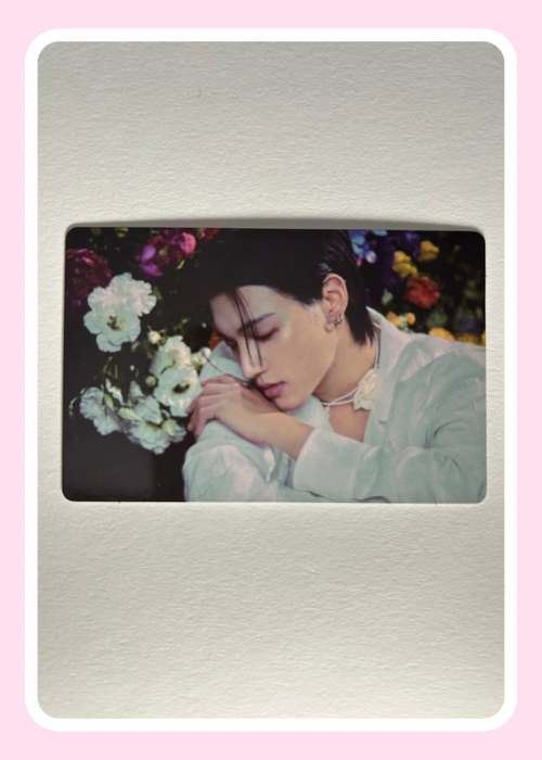 Wooyoung from Ateez looking down with flowers in the background. beautiful